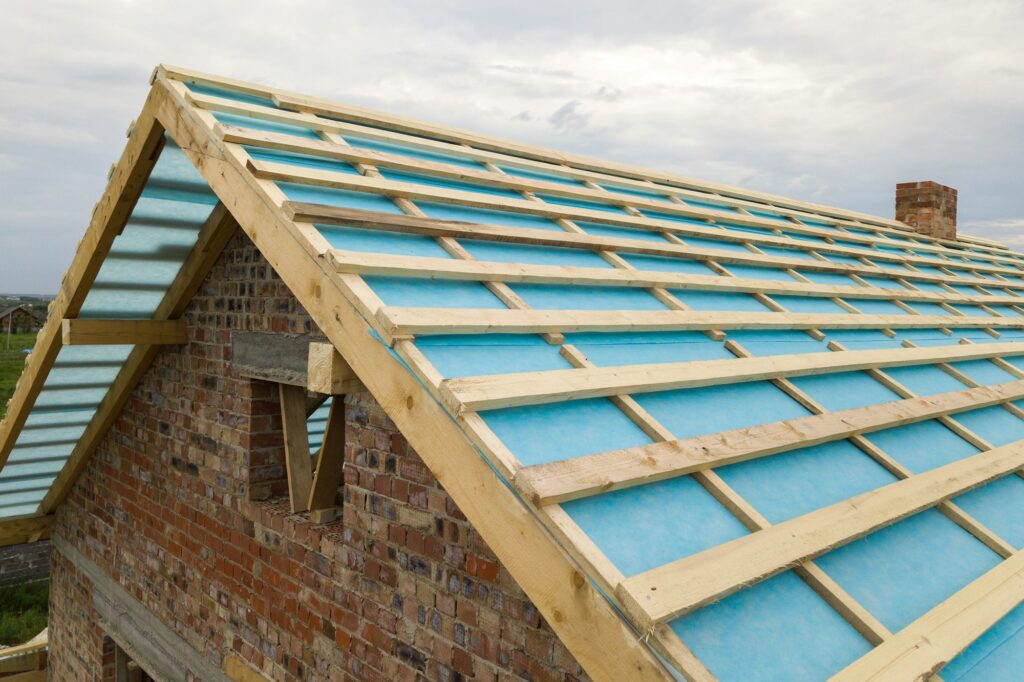 Aerial view of a brick house with wooden roof frame under construction
