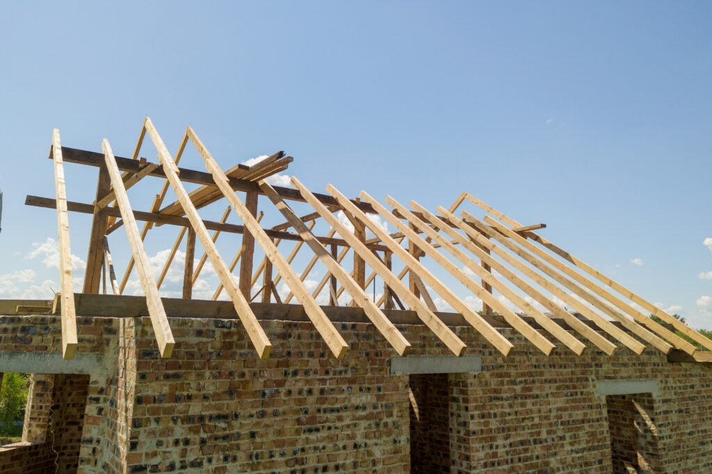 Aerial view of unfinished house with wooden roof frame structure under construction