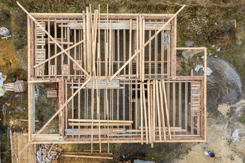 Top down aerial view of a house under construction with wooden roof frame