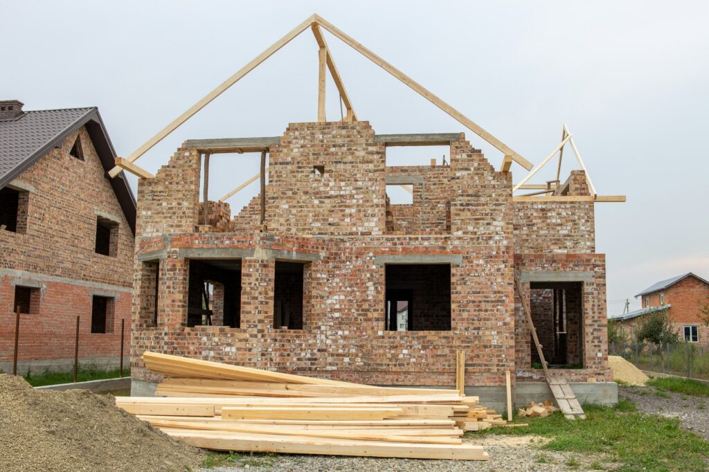 Unfinished brick house with wooden roof structure under construction