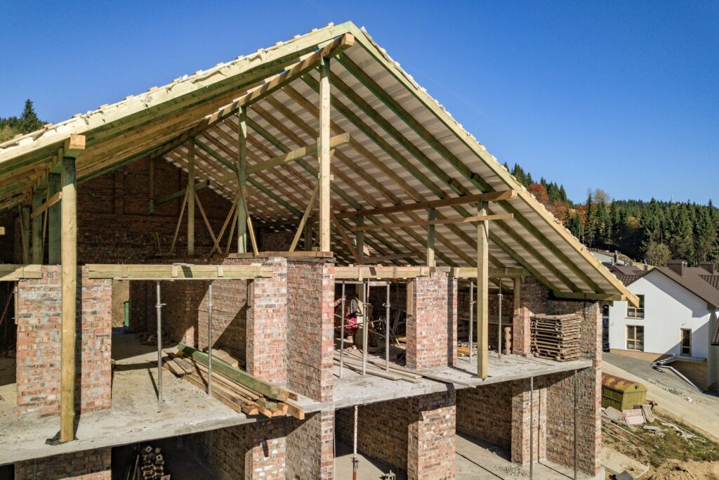 Wooden frame of new roof on a brick big house under construction